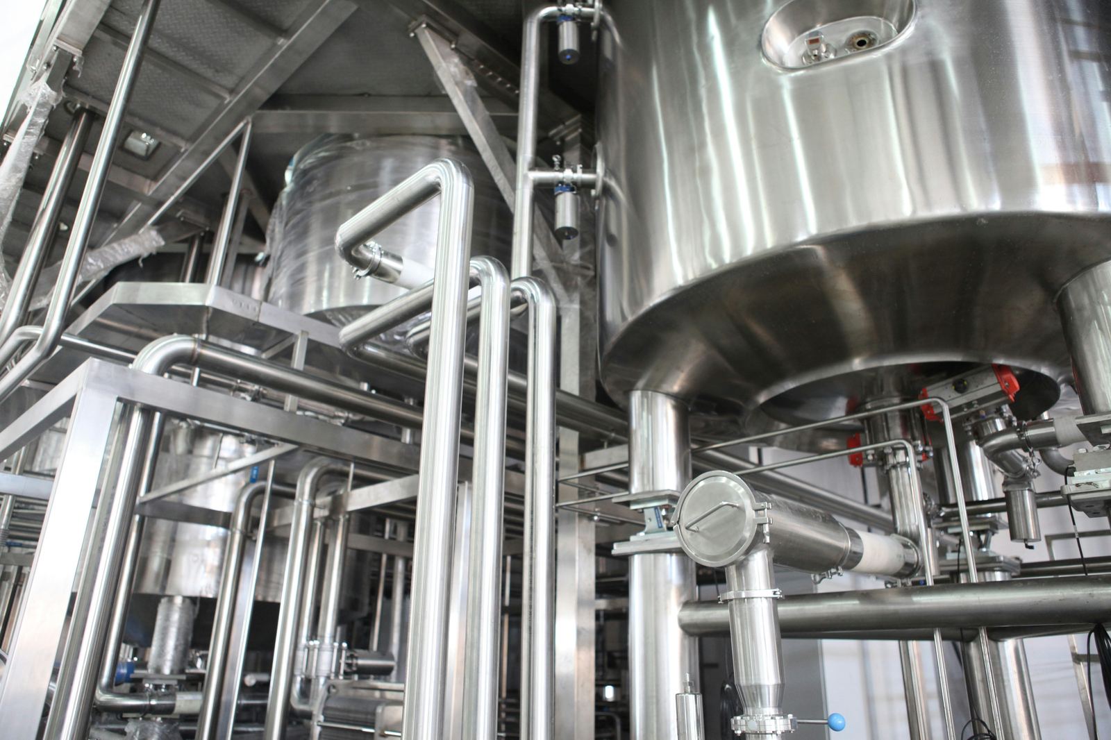 Stainless steel processing tanks and piping on the plant floor